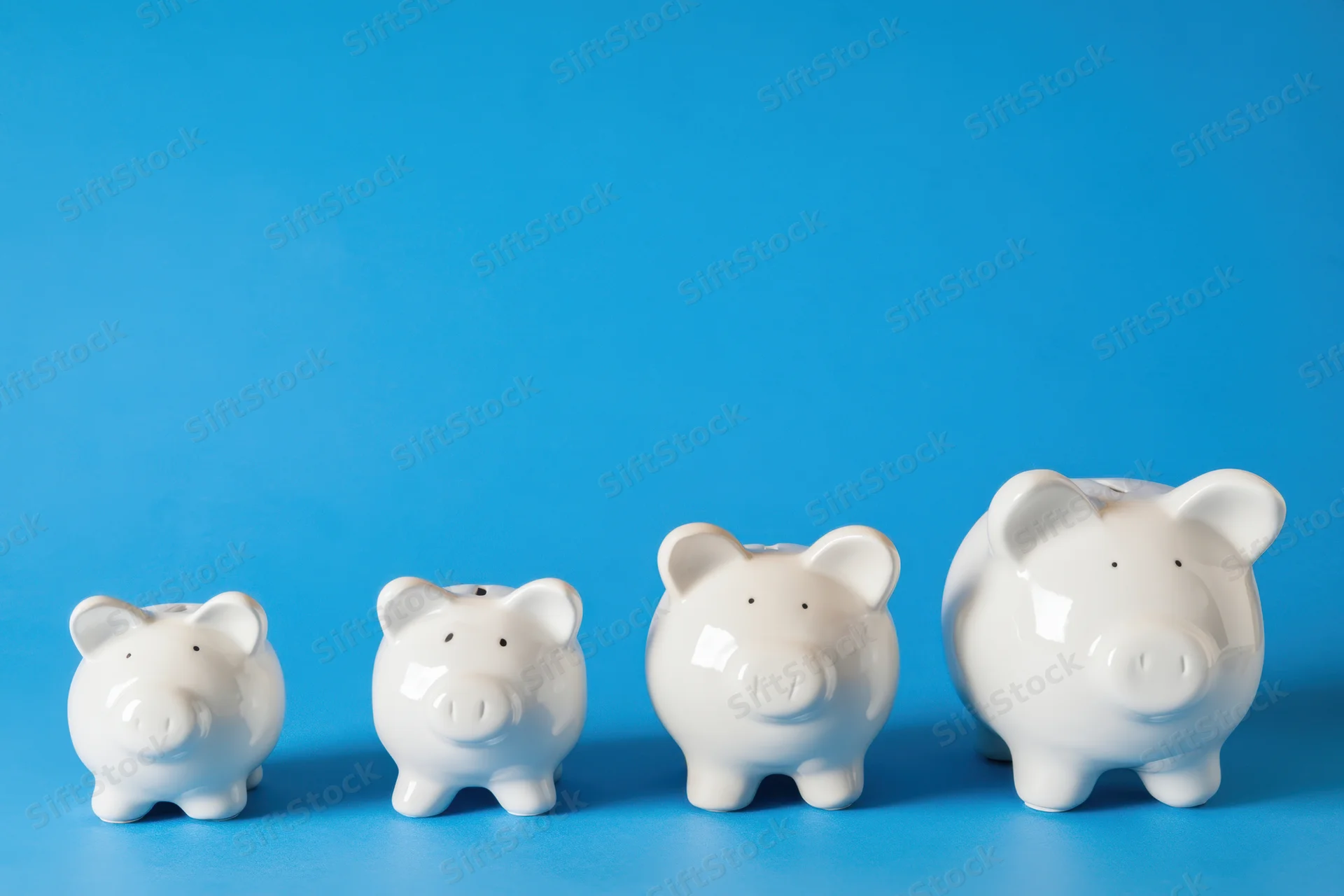 Four white ceramic piggy banks arranged in increasing size on a blue background