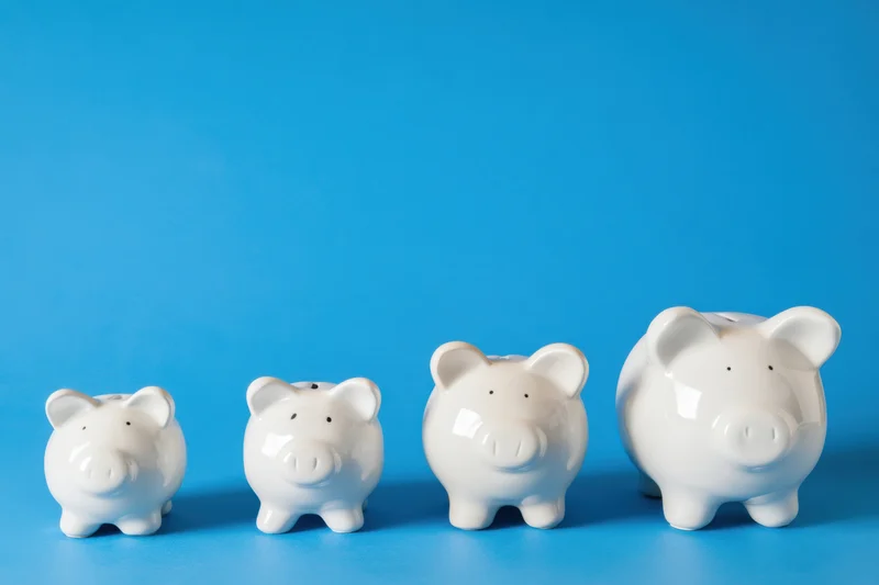 Four white ceramic piggy banks arranged in increasing size on a blue background