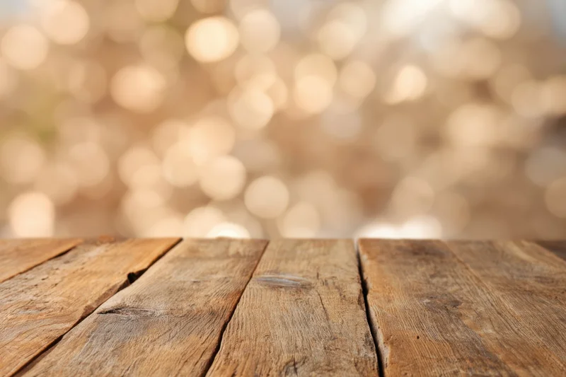 Rustic wooden table surface with blurred golden bokeh lights in background