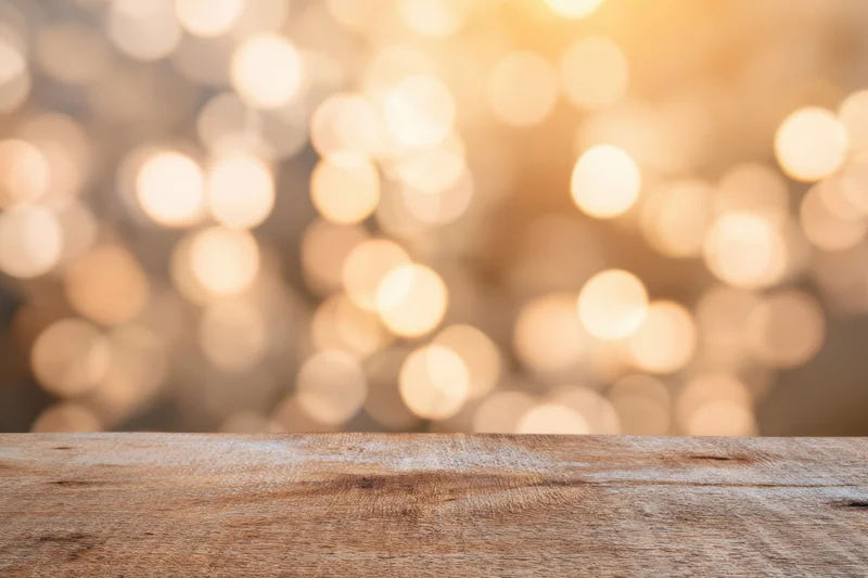 Rustic wooden table top with warm golden bokeh lights in background