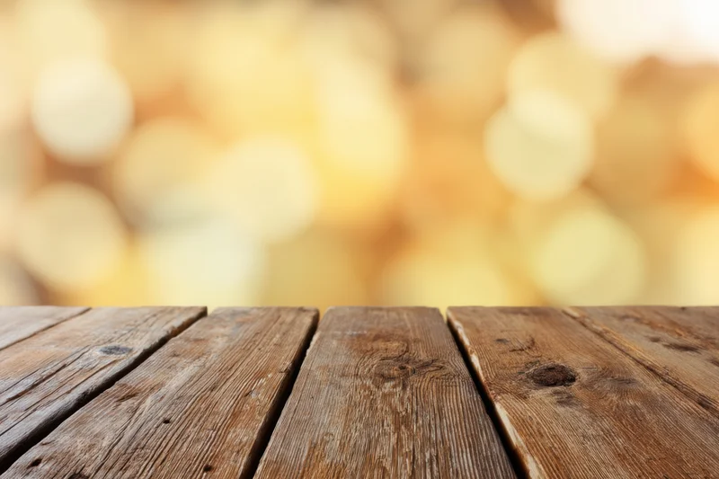 Rustic wooden table surface with warm golden bokeh background and copyspace for product display