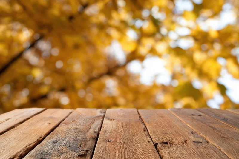 Rustic wooden table in foreground with golden autumn foliage blurred in background