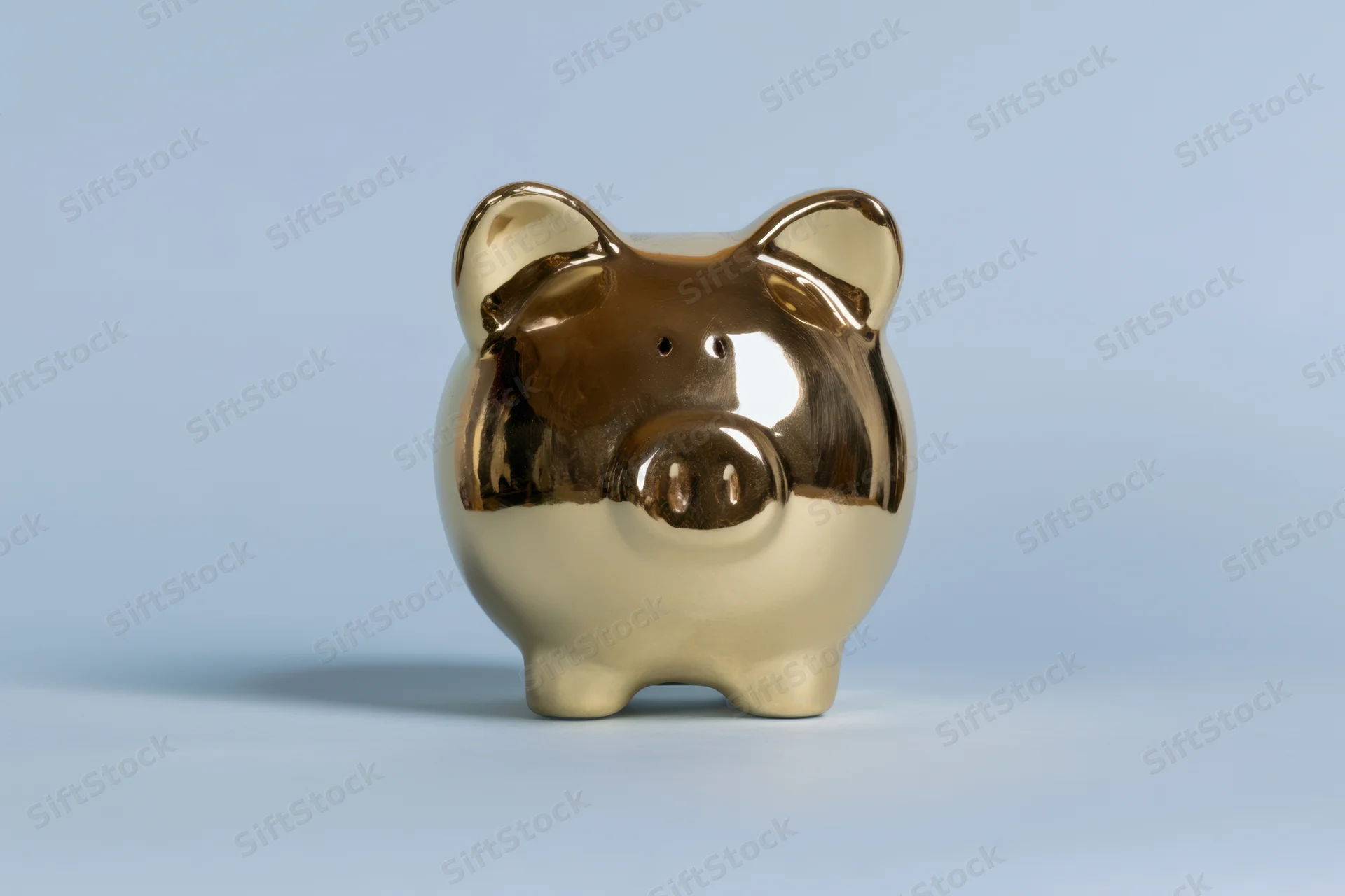 Shiny gold piggy bank standing on a smooth surface against a light blue background