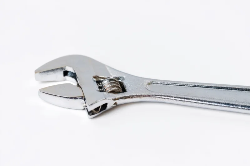 Shiny silver adjustable wrench laid flat on a white surface