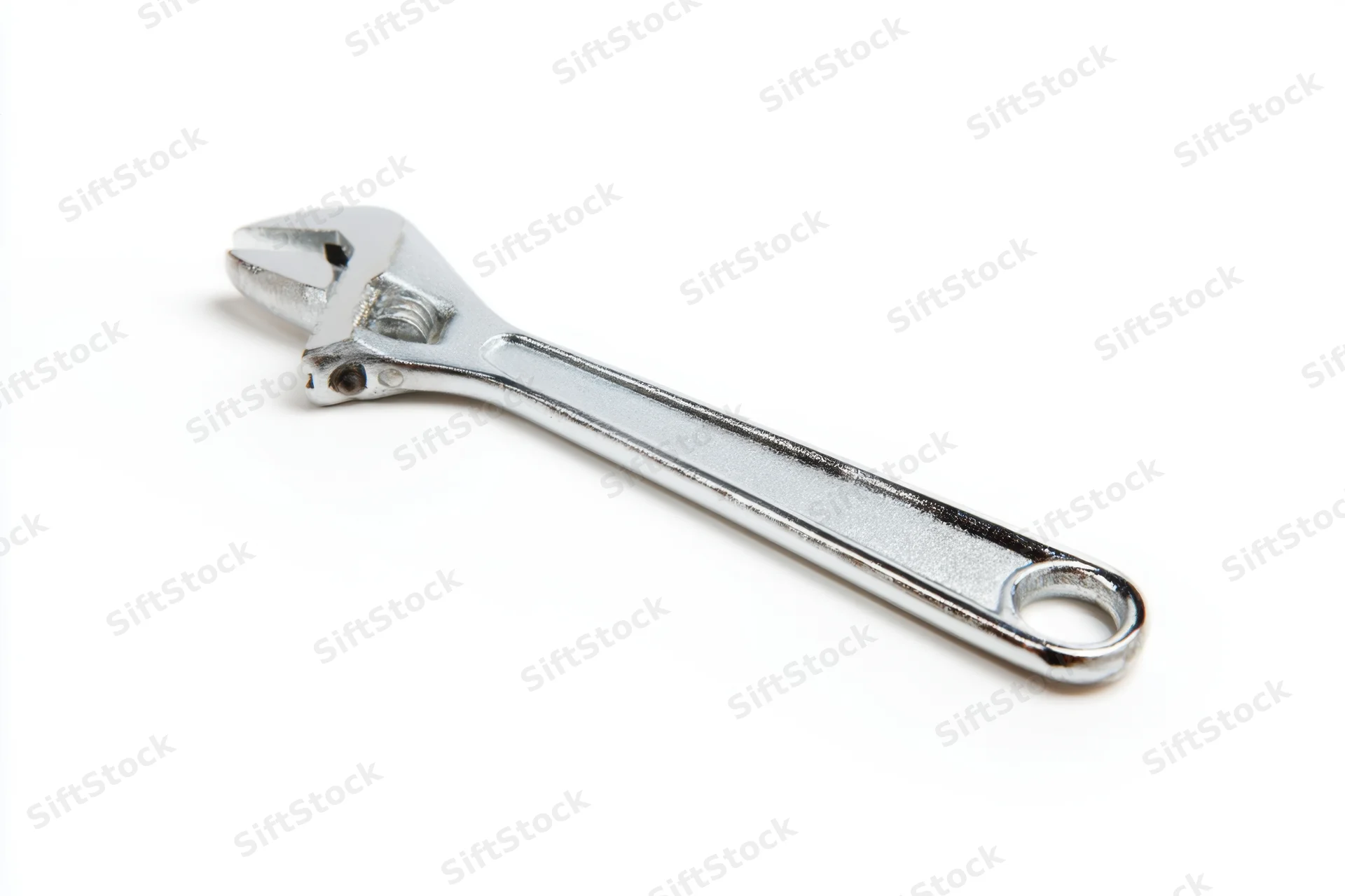 Shiny silver adjustable wrench laid flat on a clean white surface