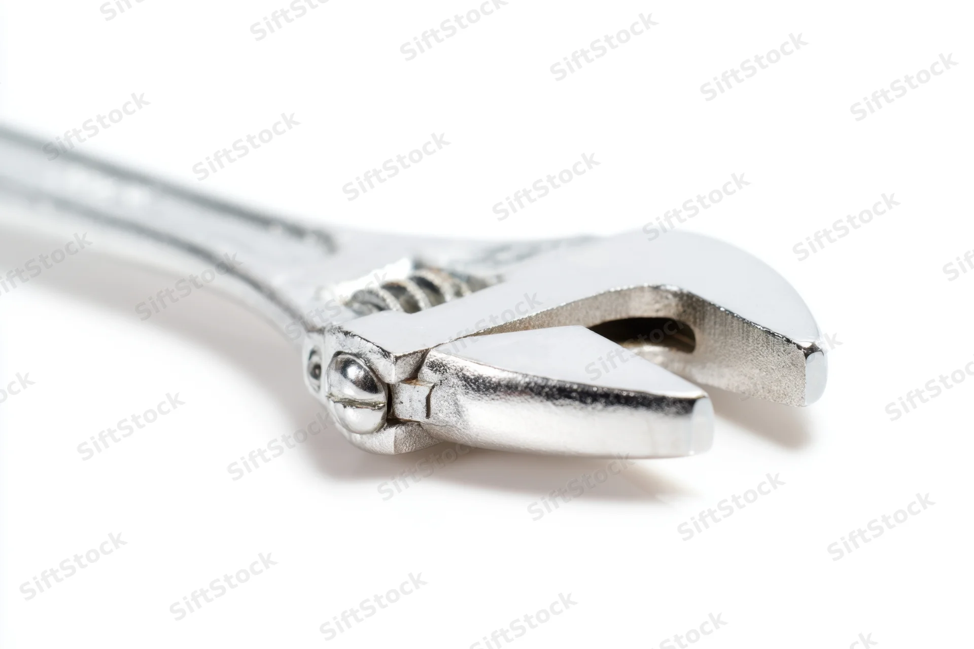 Shiny silver adjustable wrench laid flat on a white surface