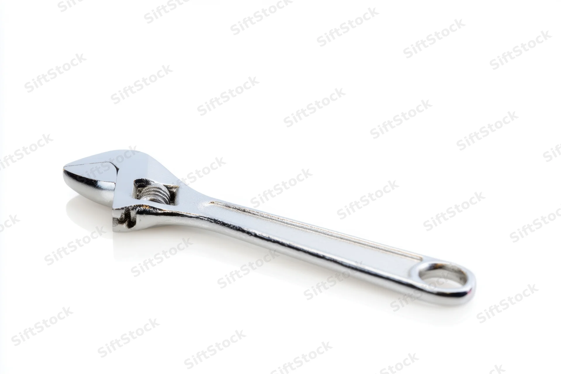Shiny chrome adjustable wrench lying flat on a white surface