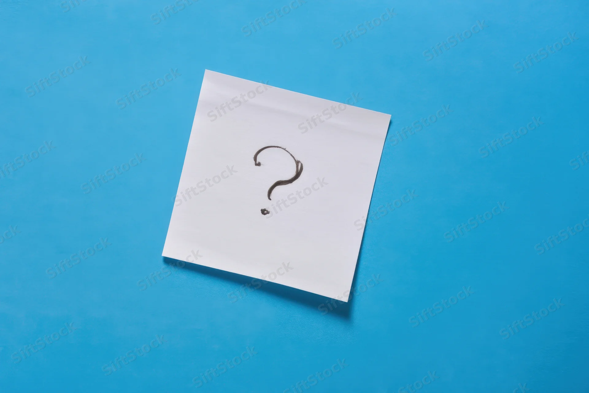 White paper note with hand-drawn question mark on blue background