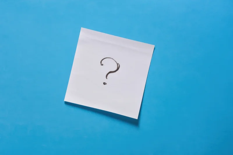 White paper note with hand-drawn question mark on blue background