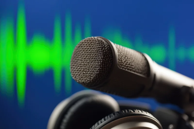 Microphone positioned above headphones with green soundwave on blue background