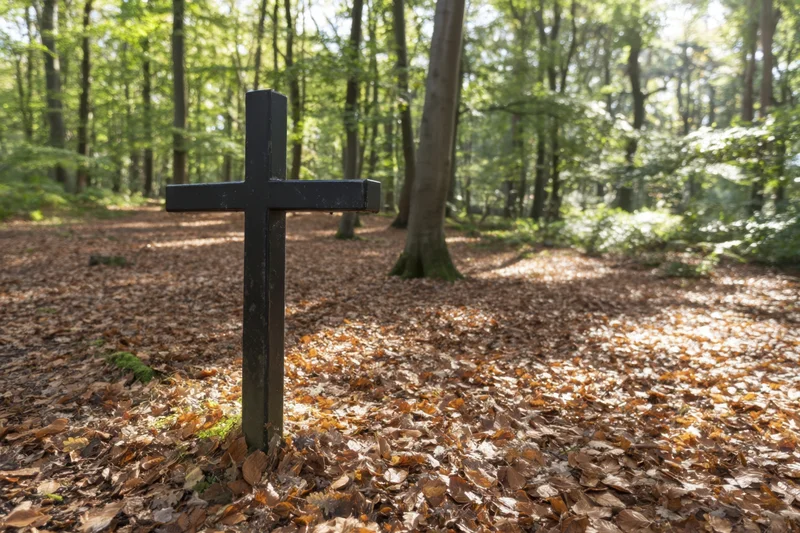 Black cross standing in a forest clearing covered with fallen autumn leaves