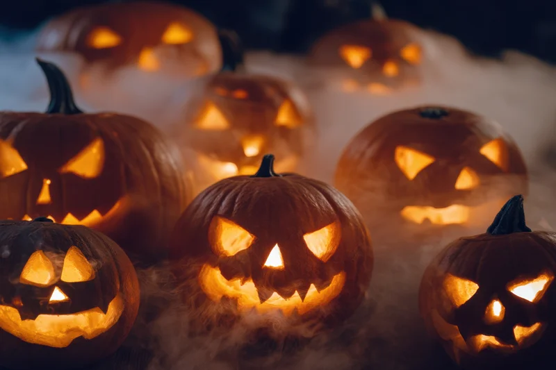 Glowing carved pumpkins arranged in a smoky dark setting for Halloween