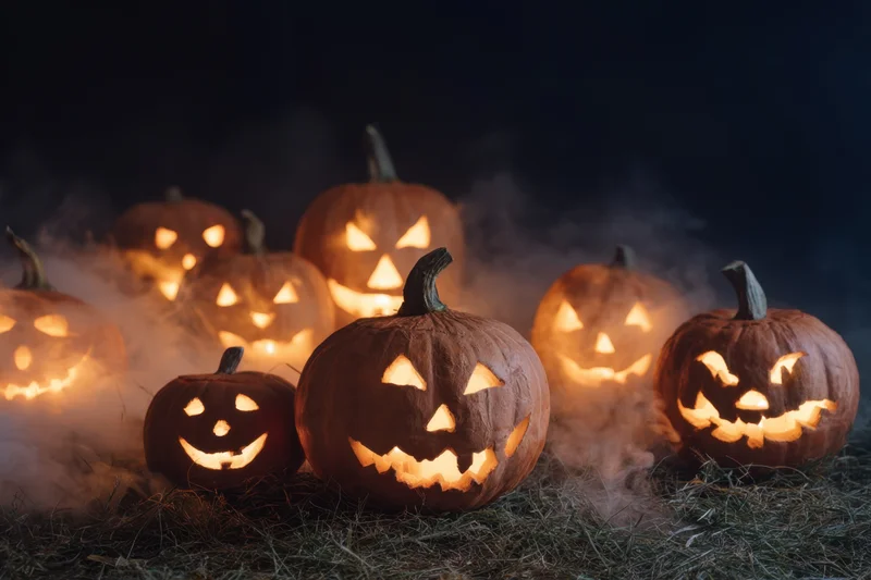 Glowing jack-o-lanterns arranged on hay with smoke in dark setting