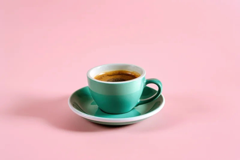 Teal coffee cup with saucer on pink background