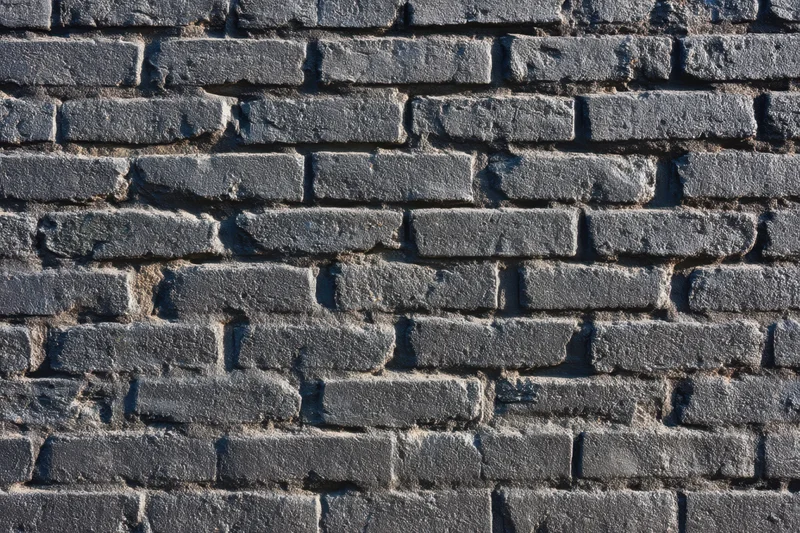 Black brick wall with visible mortar and weathered texture showing aged masonry surface