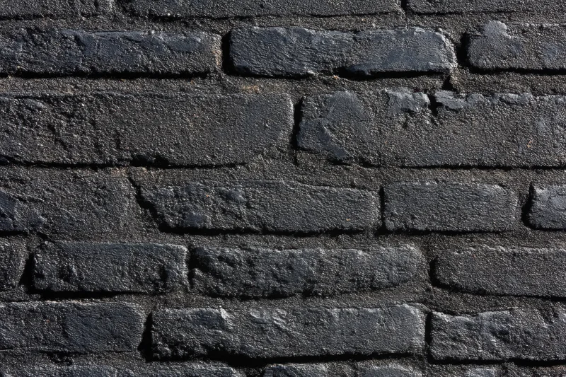 Black brick wall with textured surface and visible mortar joints