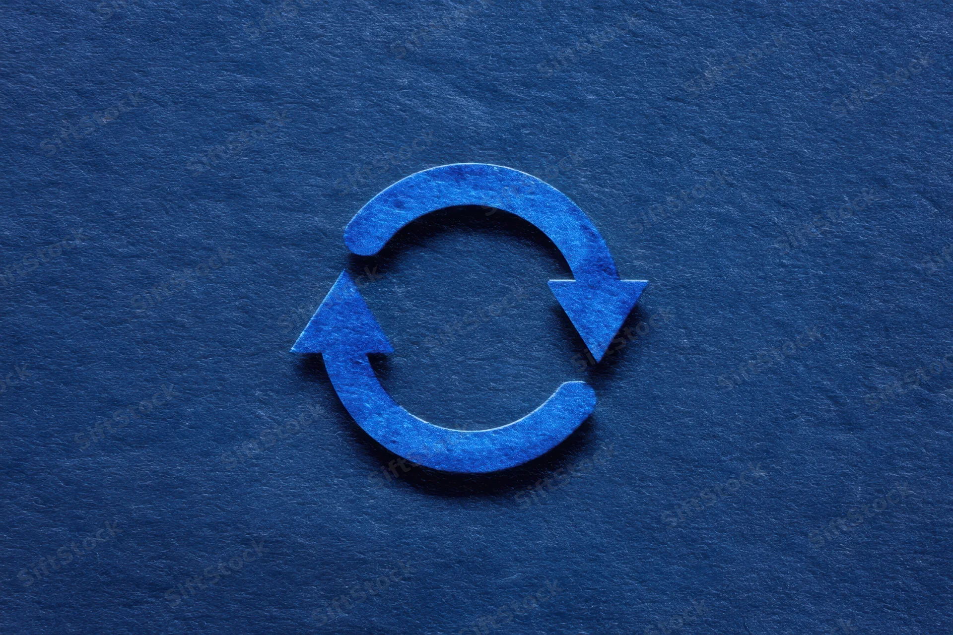 Circular recycling symbol with two blue arrows on a dark textured background
