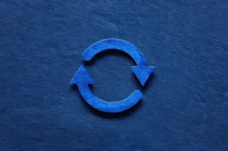 Circular recycling symbol with two blue arrows on a dark textured background
