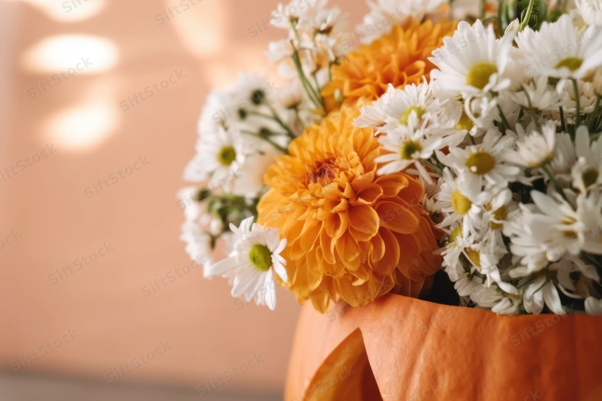 Floral arrangement of white daisies and orange chrysanthemums in a carved pumpkin vase on a warm-lit surface with bokeh background