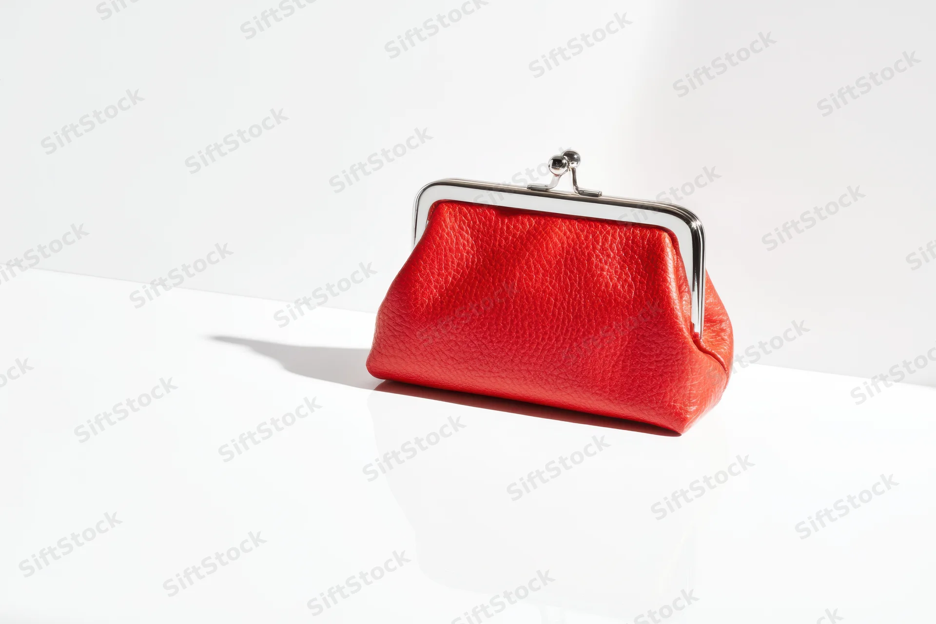 Red coin purse with silver clasp on white surface