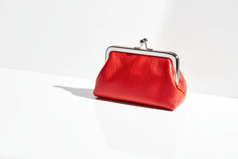 Red coin purse with silver clasp on white surface