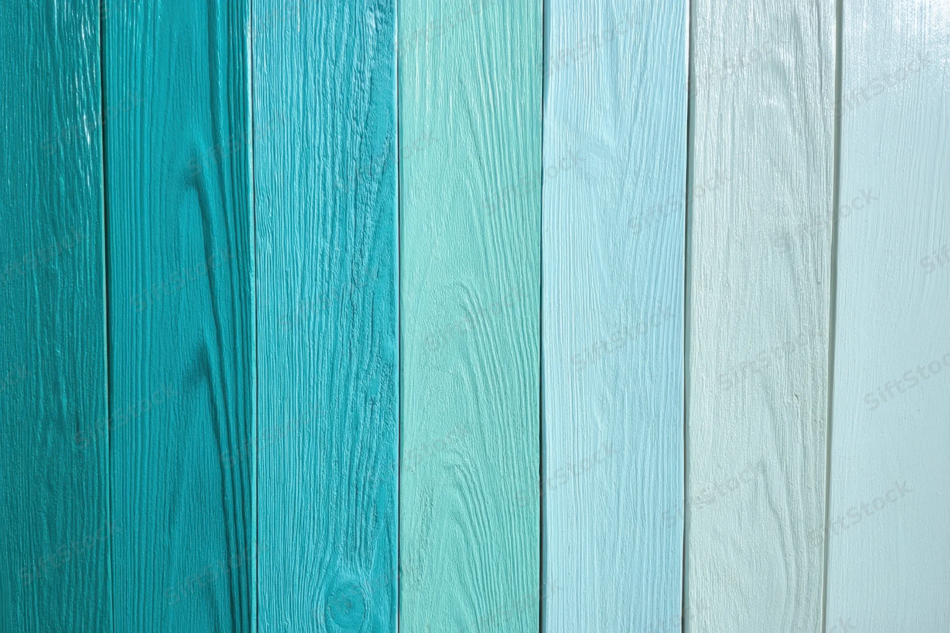 Vertical wooden panels arranged in a gradient from deep teal to white forming a wall surface