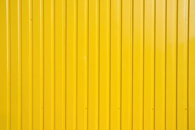 Vibrant yellow corrugated metal wall with vertical panels forming a uniform exterior surface