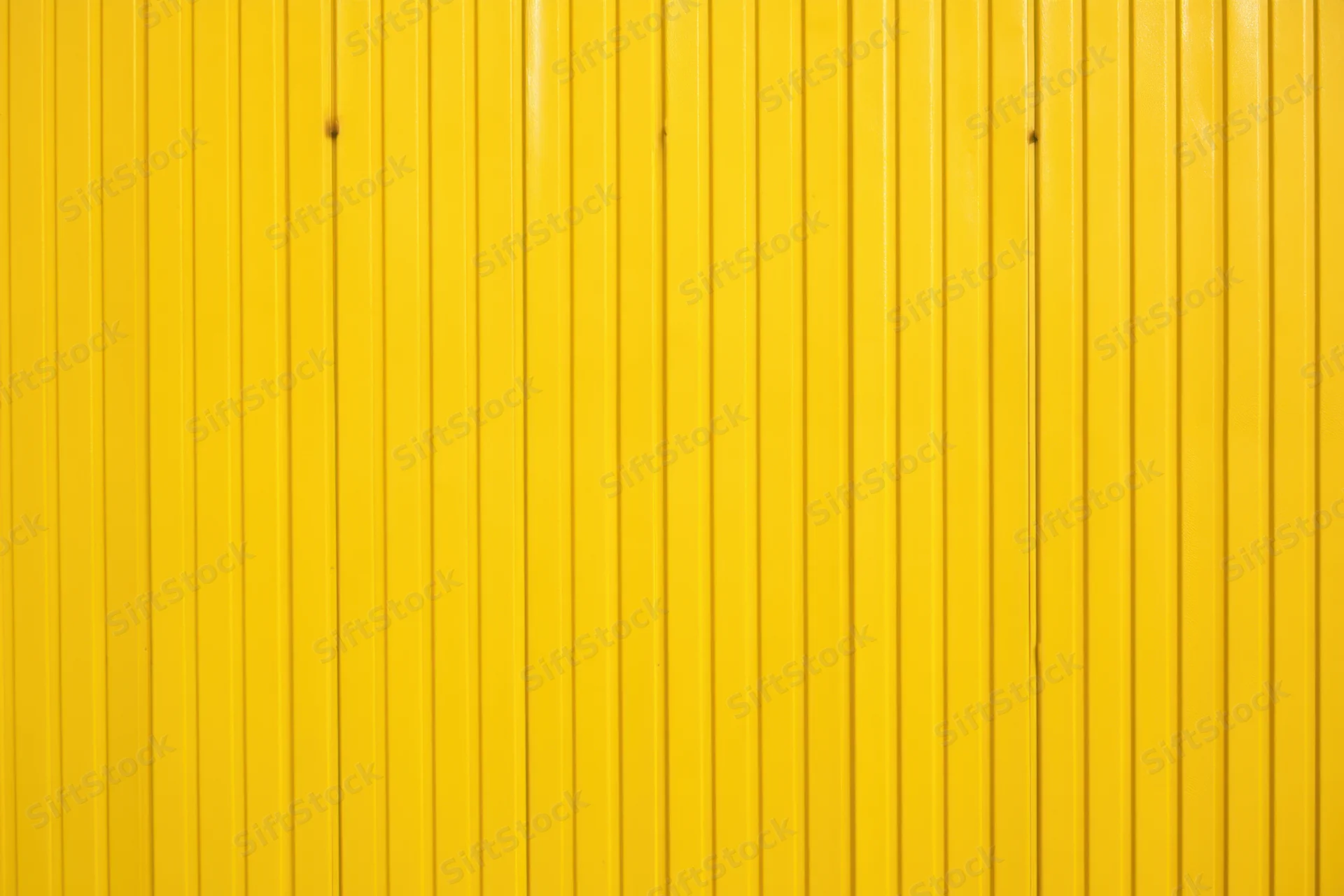 Vibrant yellow corrugated metal wall with vertical panels forming a smooth uniform surface