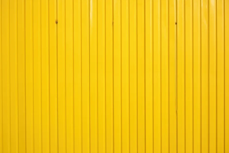 Vibrant yellow corrugated metal wall with vertical panels forming a smooth uniform surface