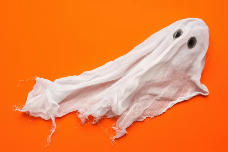 Whimsical ghost made of flowing tattered white sheet on orange background