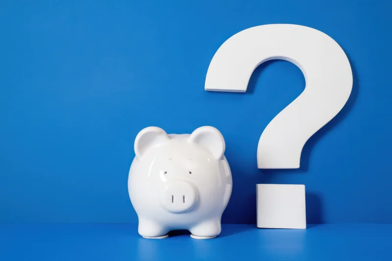 White piggy bank with friendly expression beside large white question mark on blue background