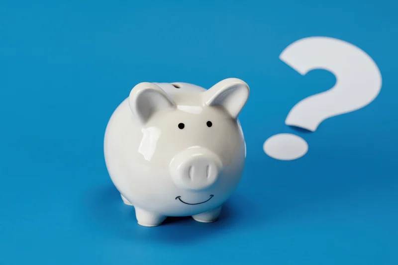 White ceramic piggy bank with smiling face and question mark on blue background
