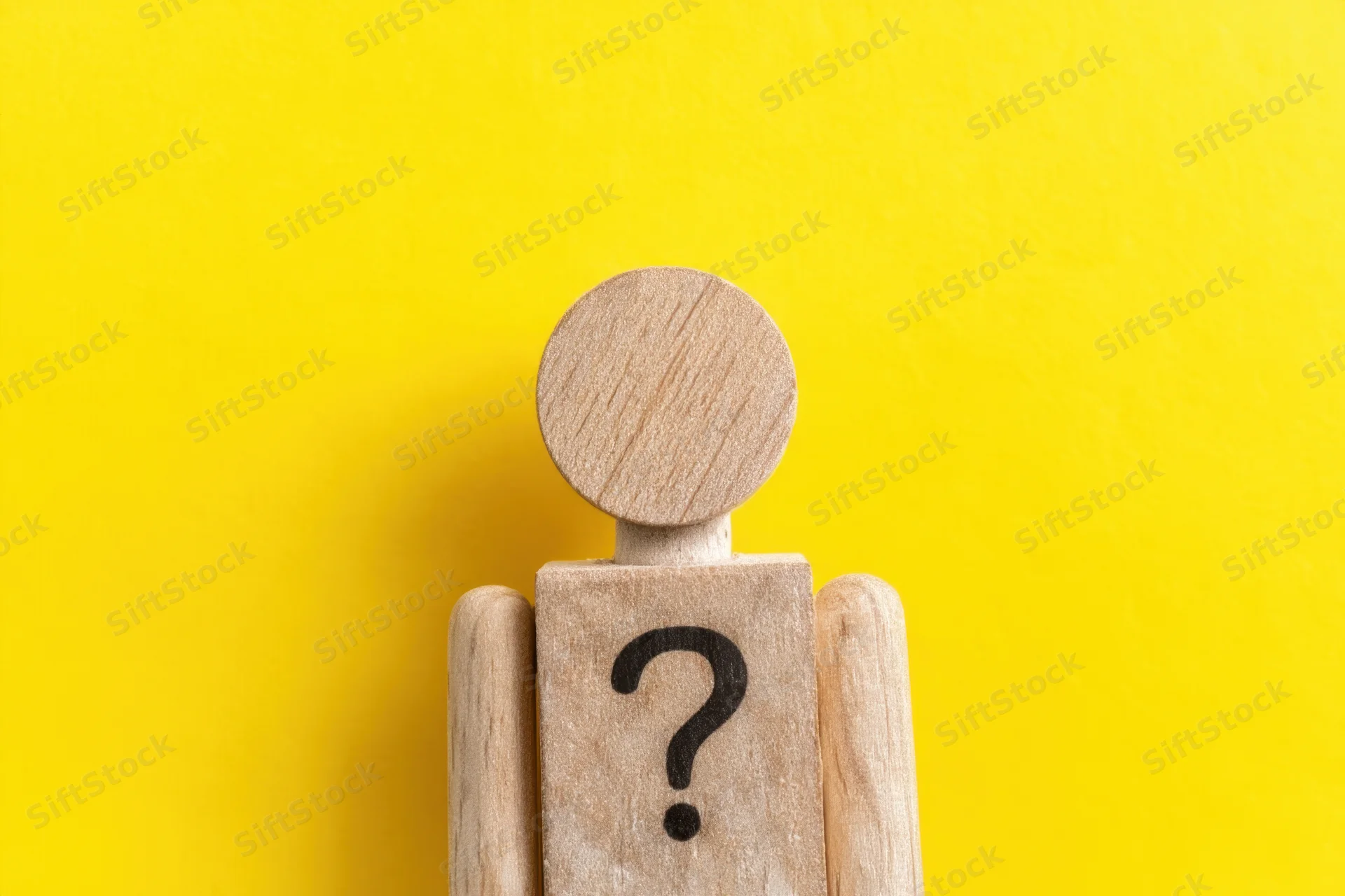 Wooden figure with question mark on torso against yellow background