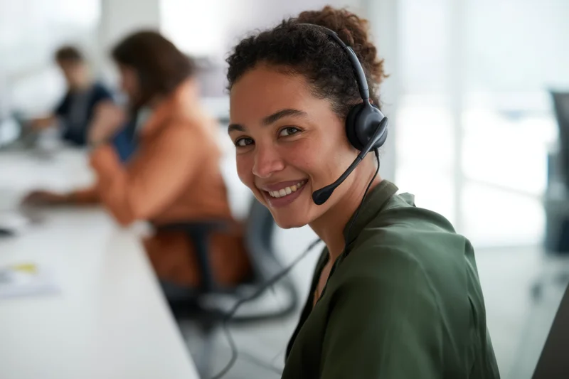 Young woman wearing headset smiling while working in office call center environment