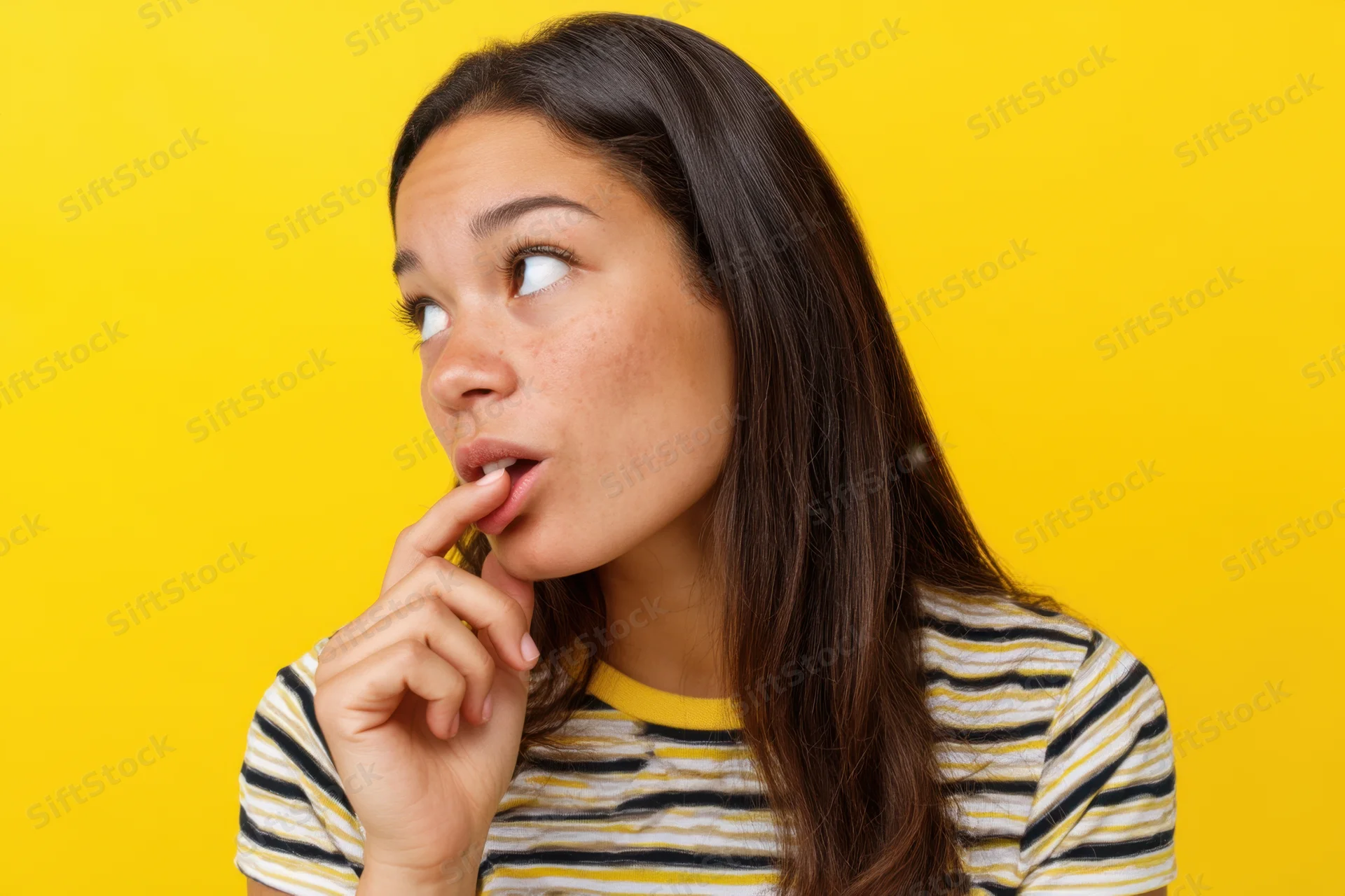 Young hispanic woman with thoughtful expression biting her lip against yellow background
