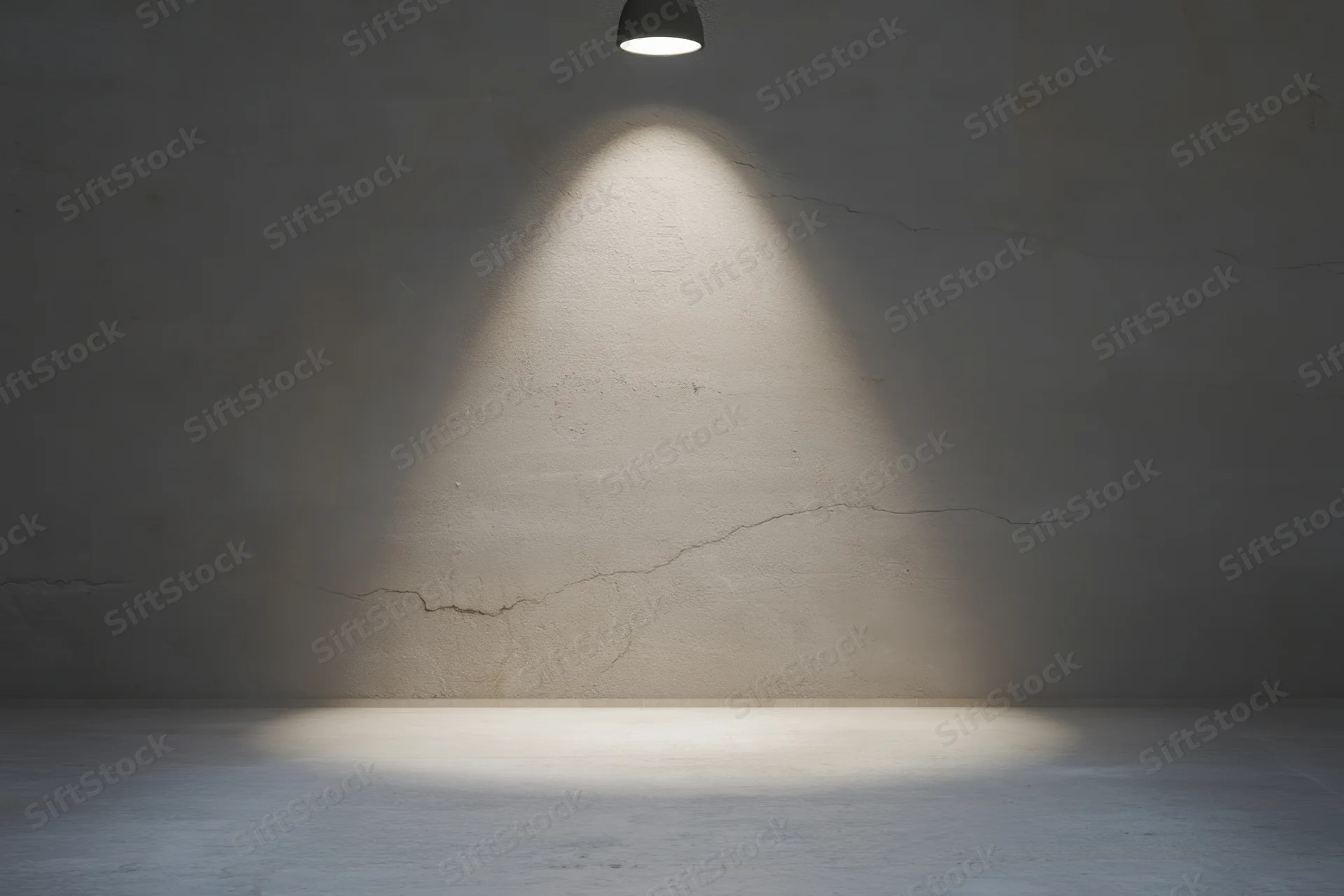 Spotlight illuminating cracked concrete wall in empty dim room