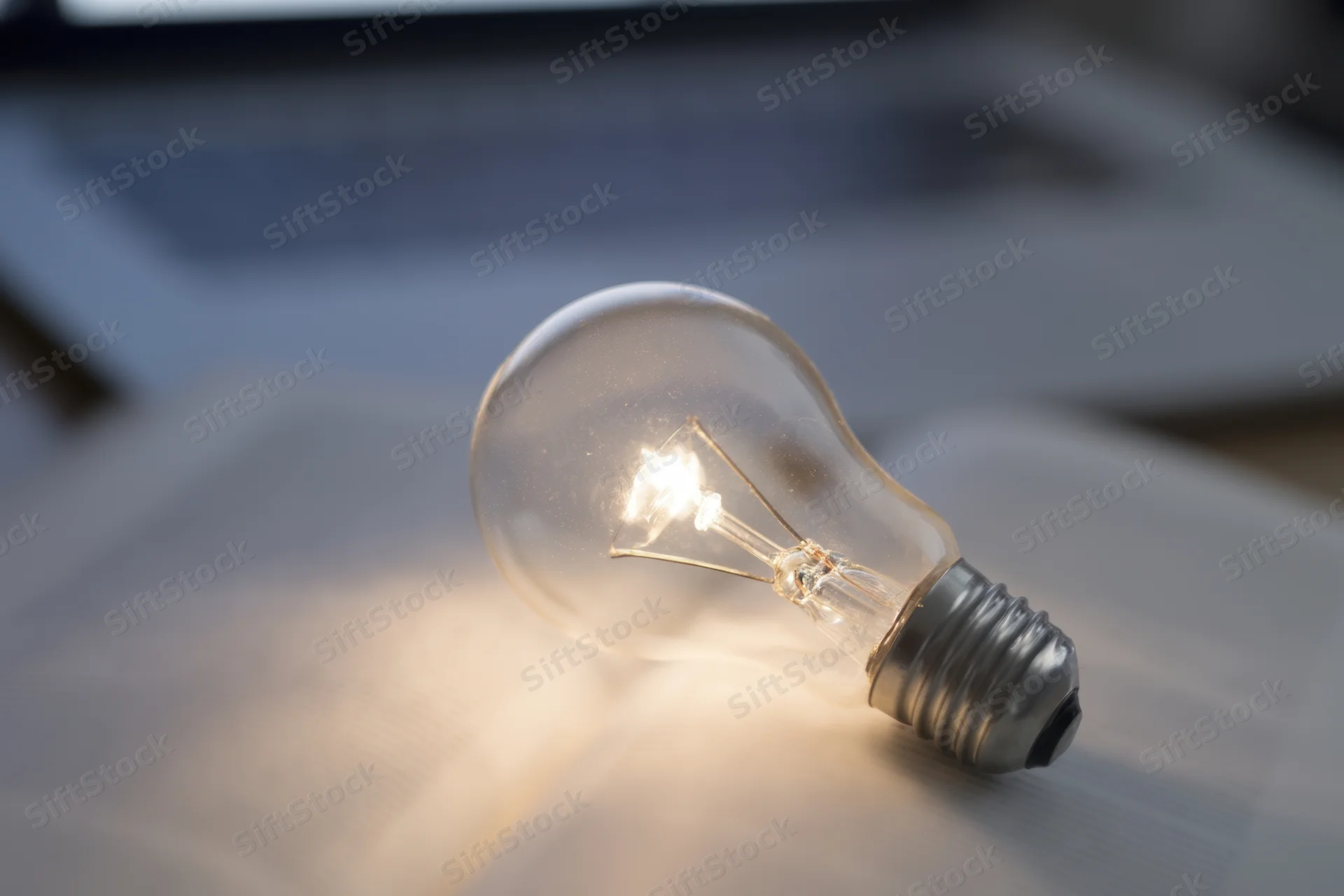Illuminated lightbulb resting on open book on desk