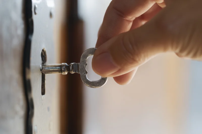 Hand inserting an ornate metal key into a vintage door lock