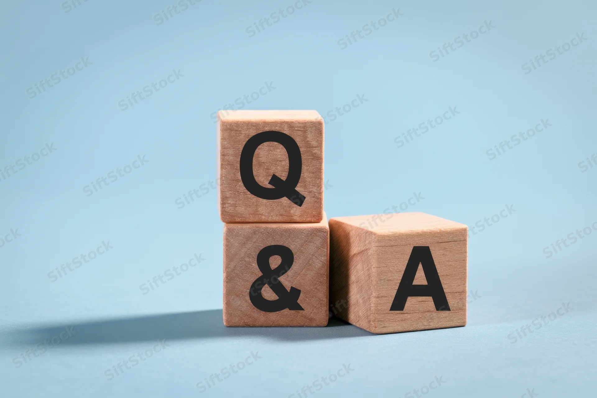 Three wooden blocks stacked with q ampersand a letters on blue background