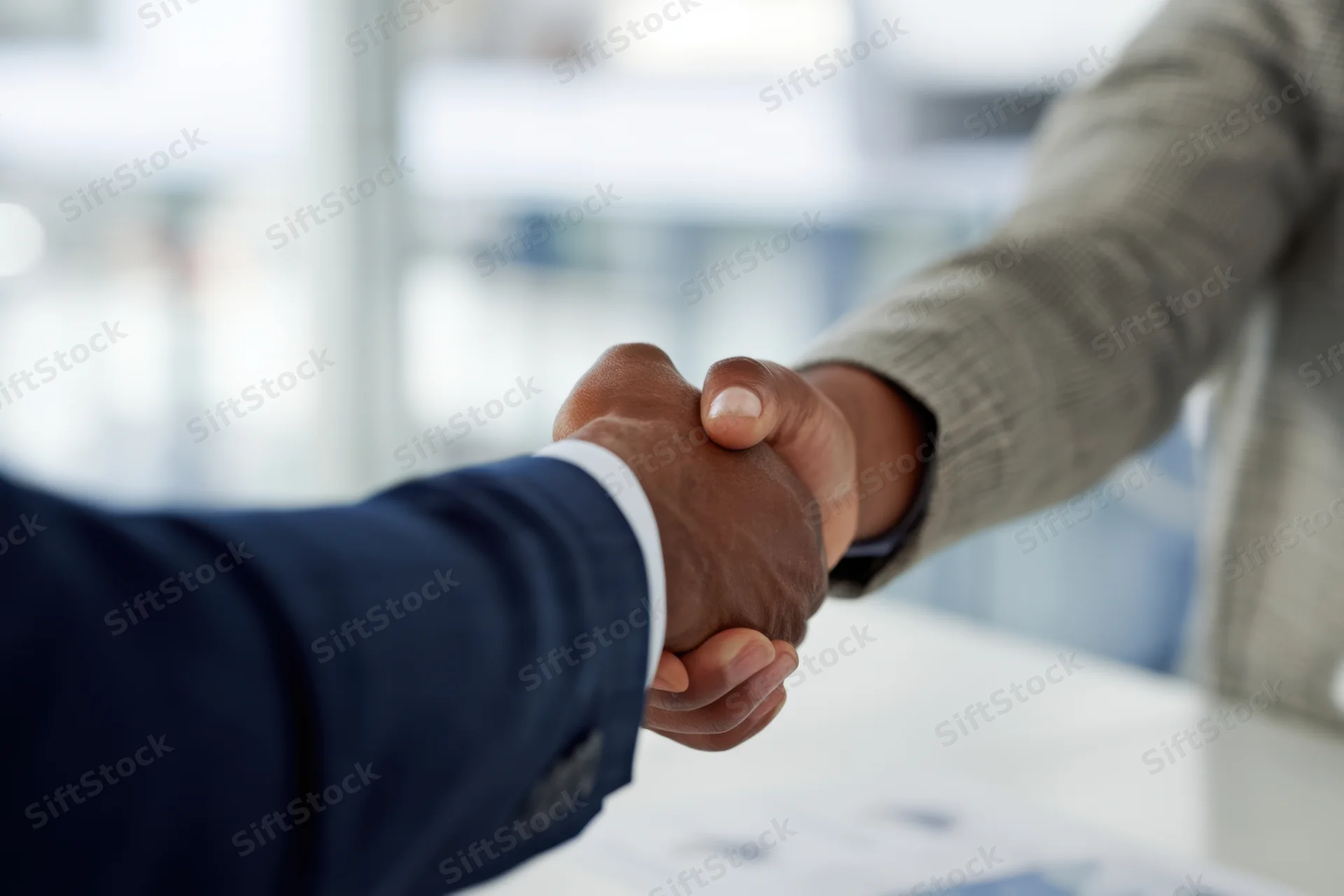Two business professionals shaking hands at a meeting in an office setting