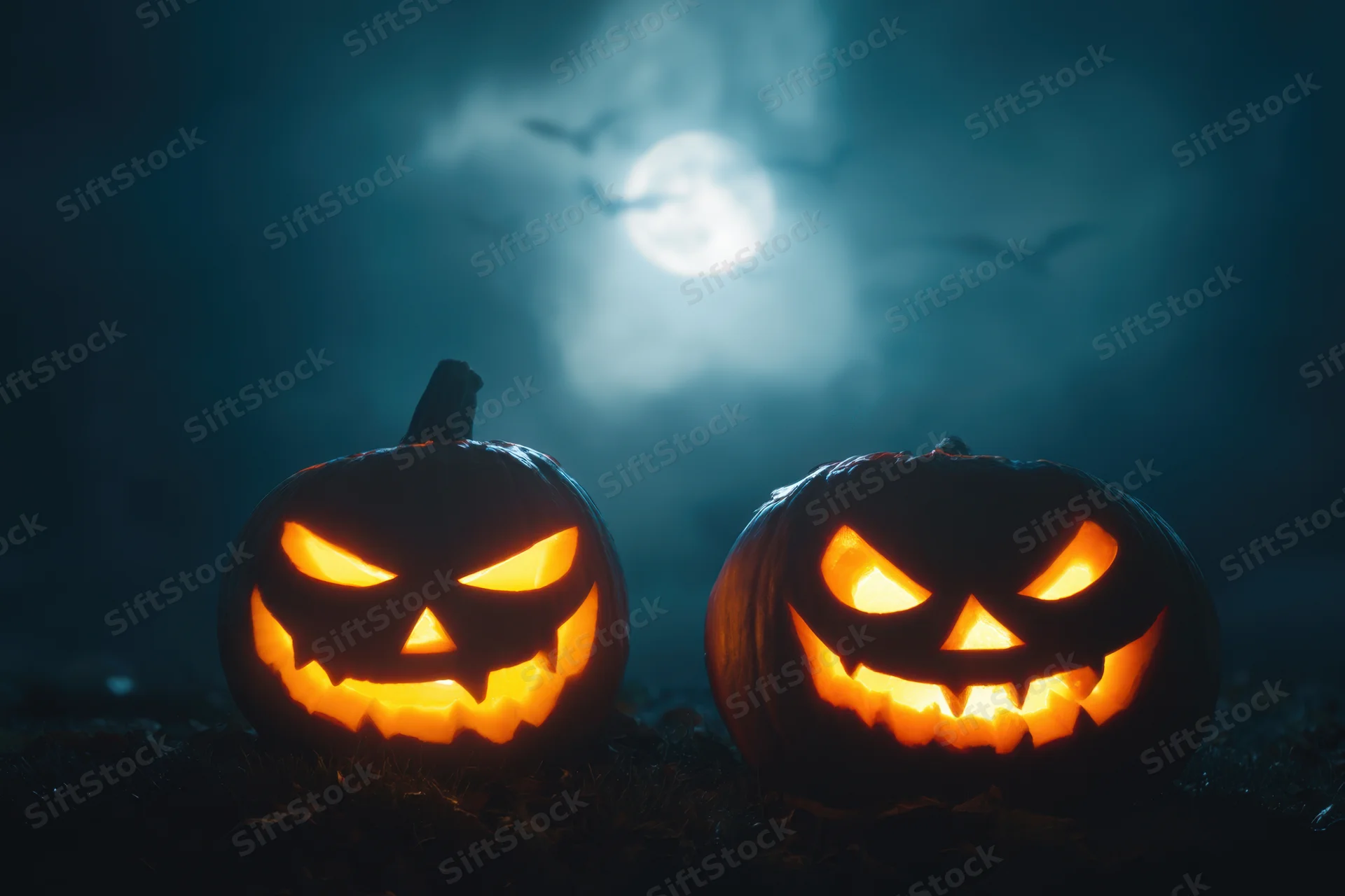 Two carved jack-o-lanterns with menacing expressions glowing in the dark under a full moon