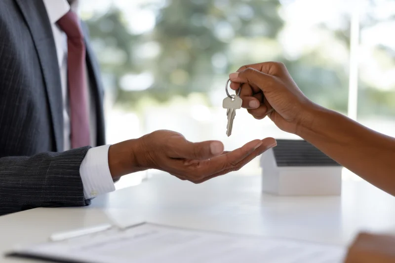 Real estate agent handing keys to buyer during property transaction in office setting