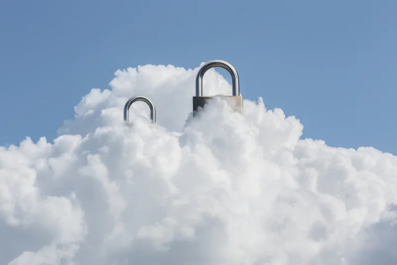 Two large padlocks emerging from fluffy white clouds against a clear blue sky