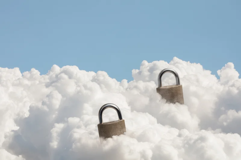Two large padlocks hovering among fluffy white clouds in a blue sky