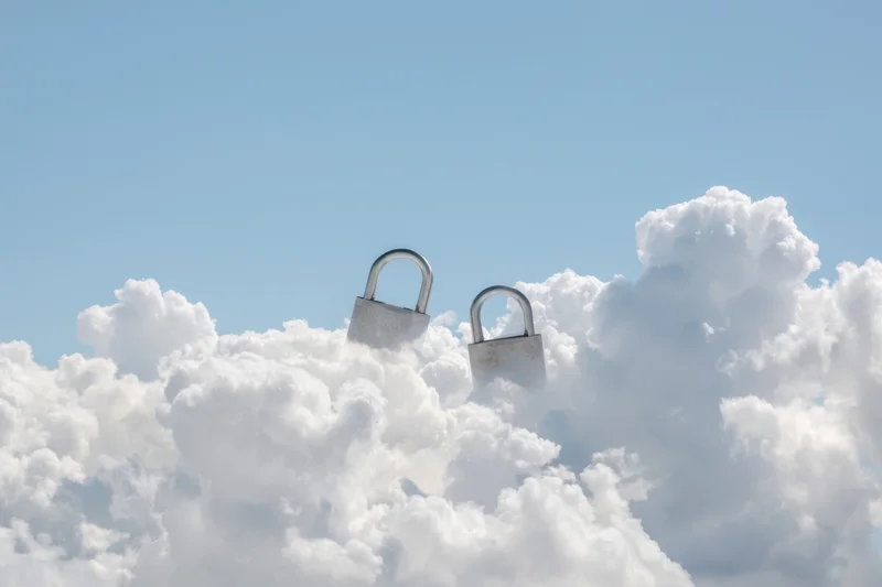 Two large padlocks hovering among fluffy white clouds in a clear blue sky