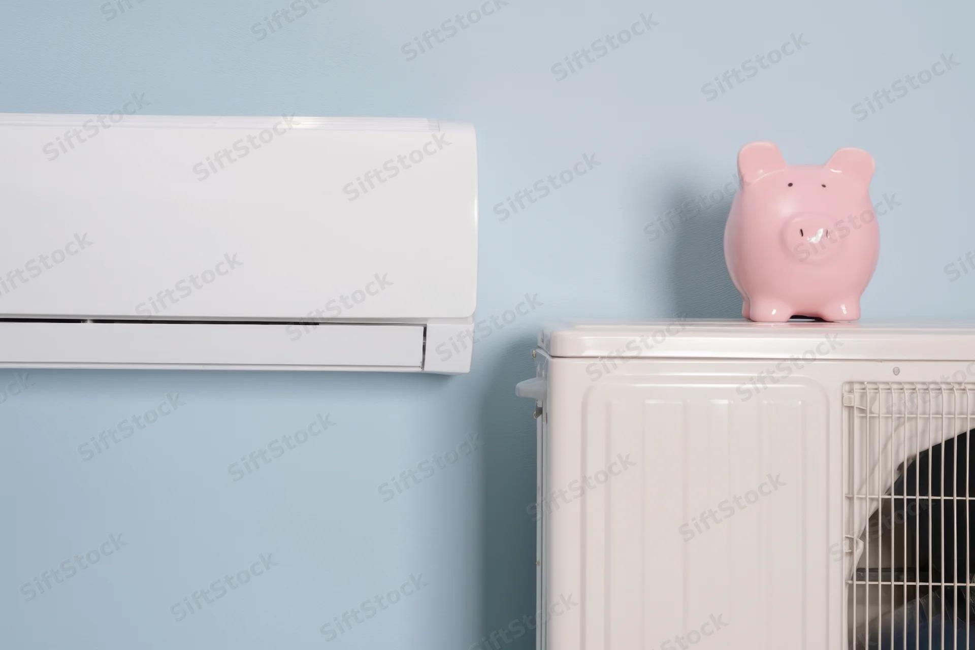 White air conditioning unit mounted on blue wall beside white appliance with pink piggy bank on top