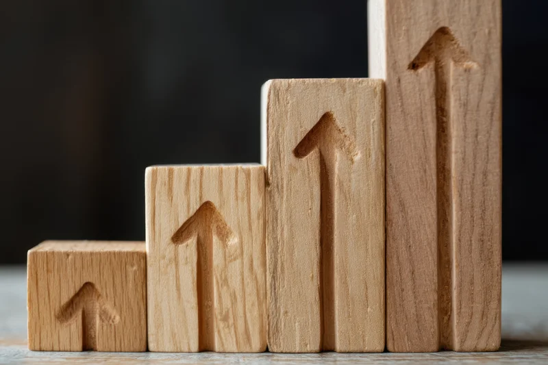 Wooden blocks arranged in ascending stair-step formation each with carved upward arrow on front face on textured surface