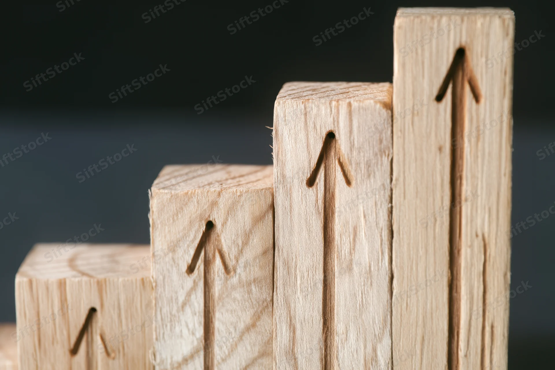 Wooden blocks arranged in ascending stair-step formation with carved arrows pointing upward