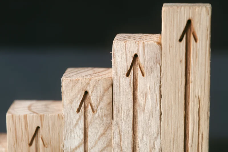 Wooden blocks arranged in ascending stair-step formation with carved arrows pointing upward