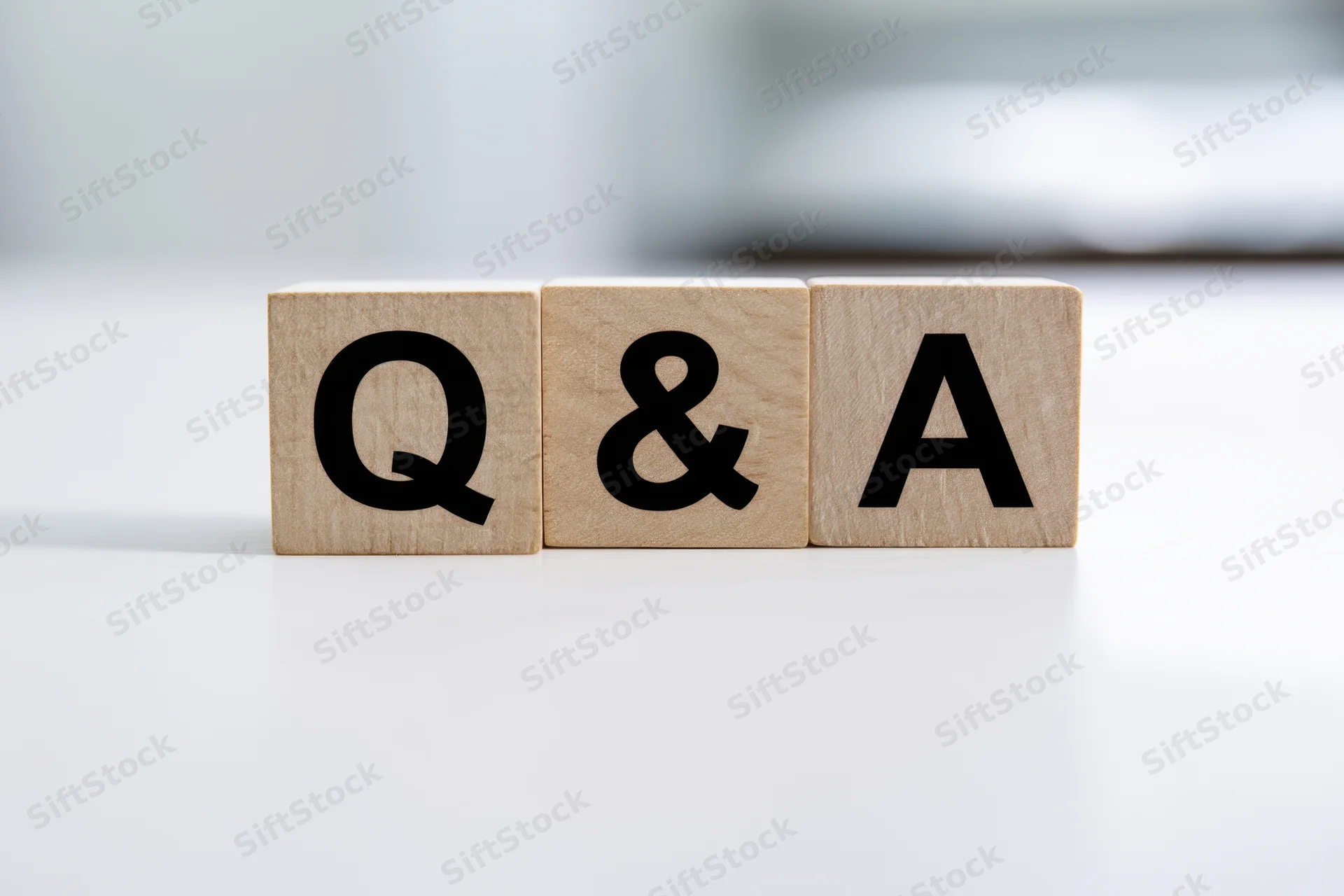 Wooden blocks with bold black letters spelling q and a arranged neatly on a white surface